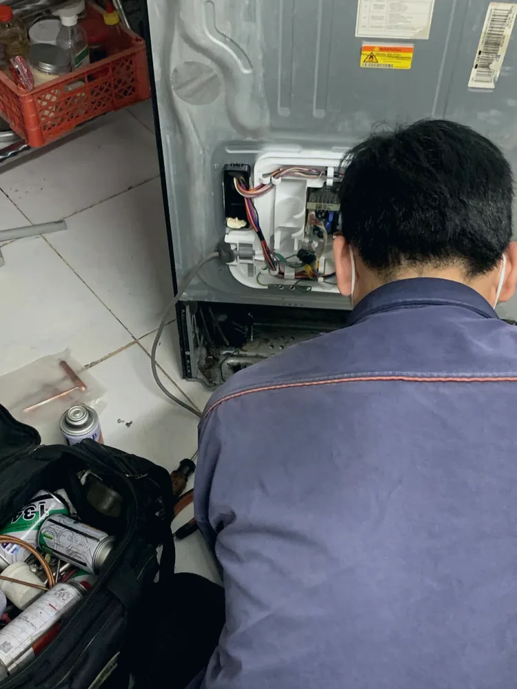 Kỹ thuật viên kiểm tra bo mạch và hệ thống làm lạnh của tủ lạnh