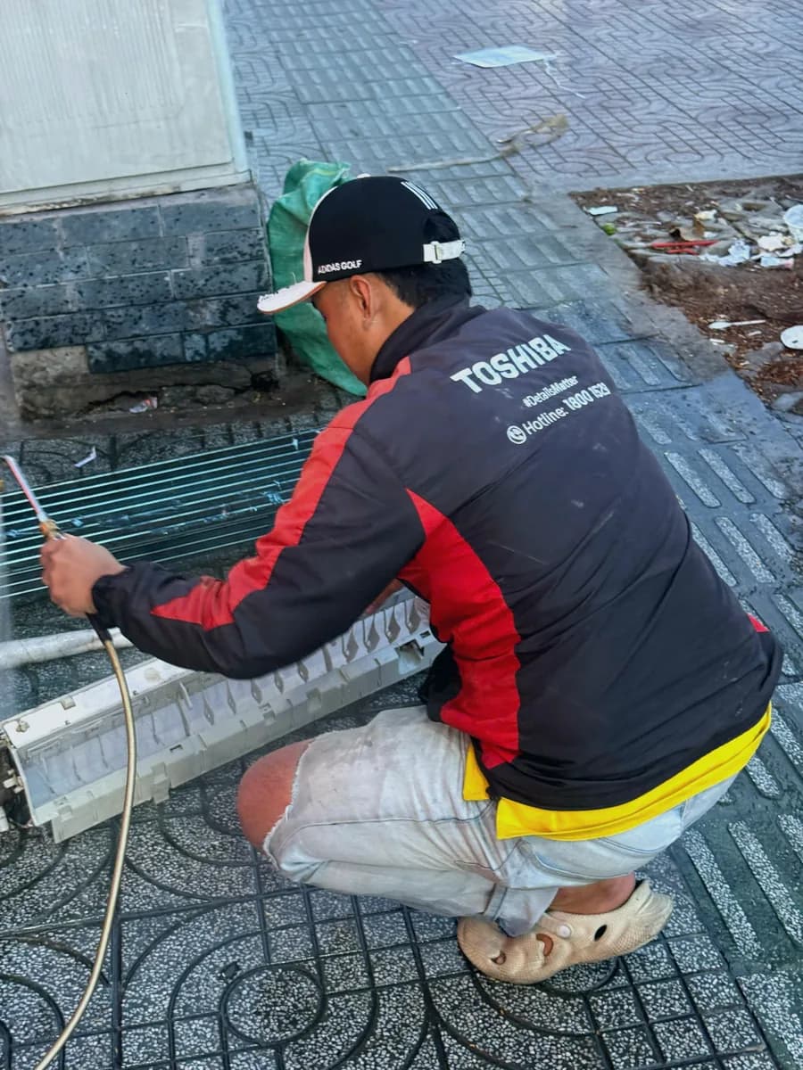 Thợ điện lạnh mặc đồng phục xịt rửa dàn lạnh máy lạnh tại nhà khách